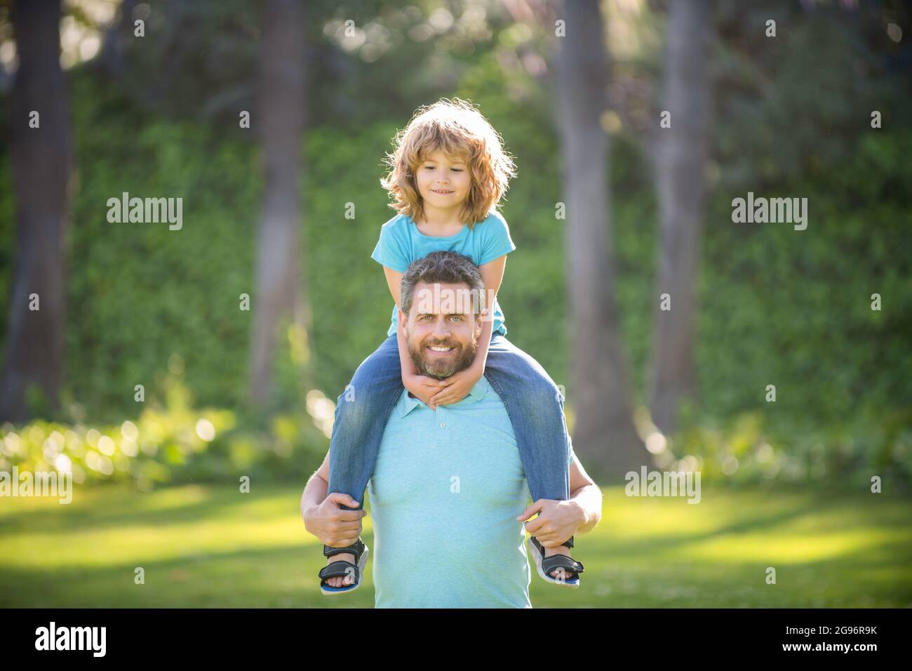 Happy father man carry boy child sitting on fathers shoulders summer outdoors, piggy-back Stock Photo