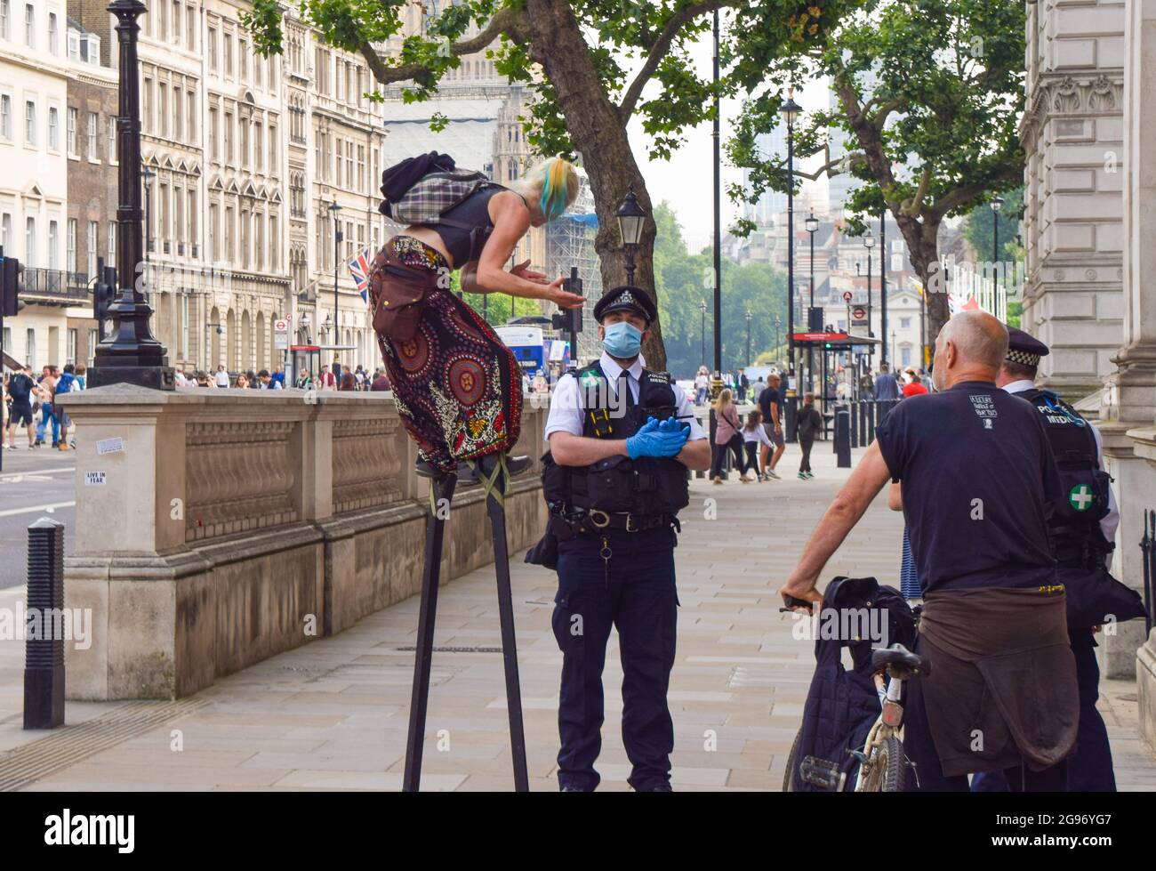 London, United Kingdom. 24th July 2021. A protester on stilts talks to a police officer in Whitehall. Thousands of protesters gathered in Westminster to protest against COVID-19 vaccinations, vaccine passports, and coronavirus restrictions, with many demonstrators calling the pandemic a 'hoax'. (Credit: Vuk Valcic / Alamy Live News) Stock Photo