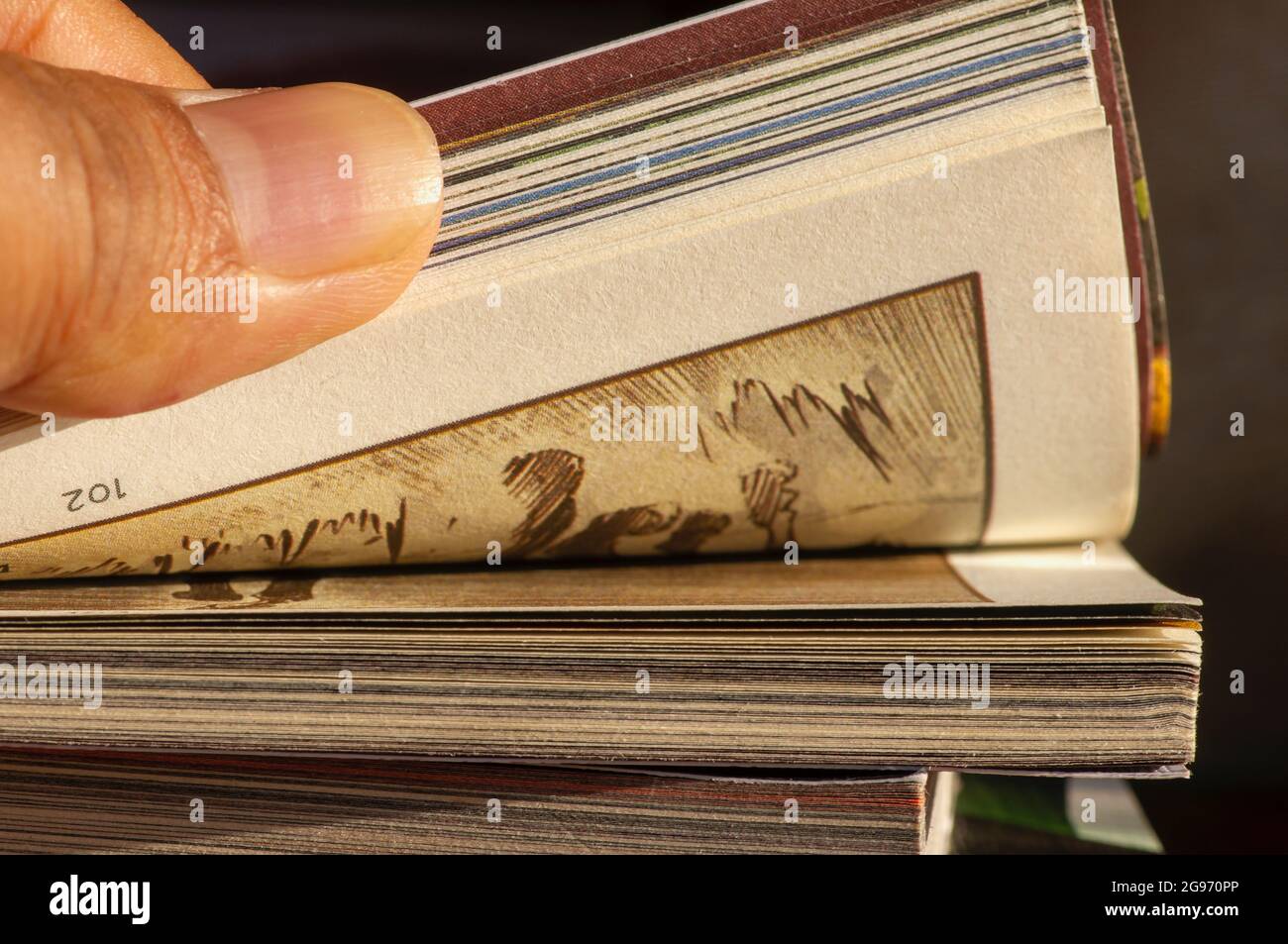 A thumb flipping pages of a comic book, selected focus. Stock Photo