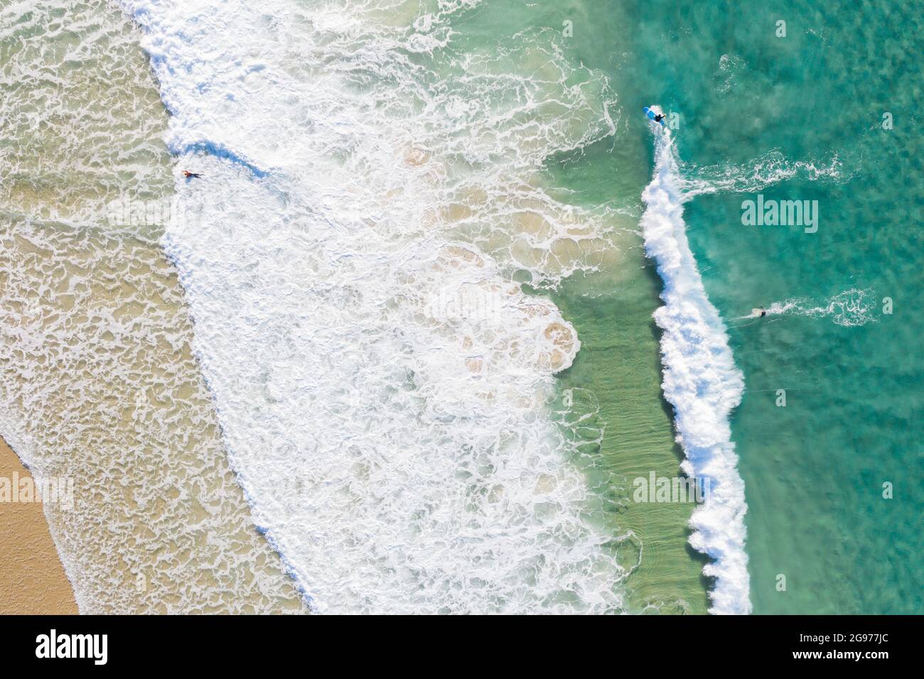 Beautiful aerial view of blue pristine water with surfers and gentle waves Stock Photo