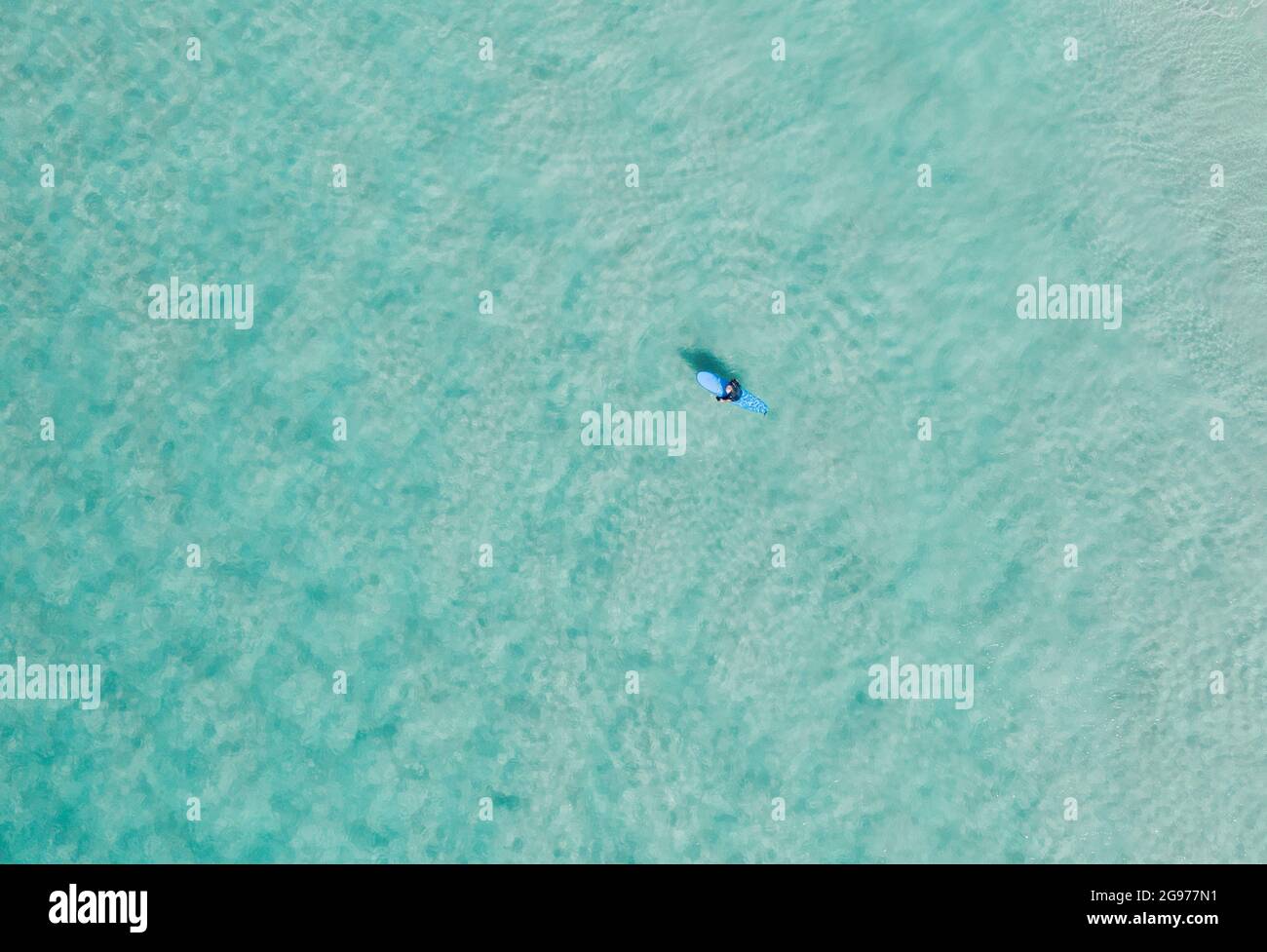 Beautiful aerial view of blue pristine water with surfers and gentle waves Stock Photo