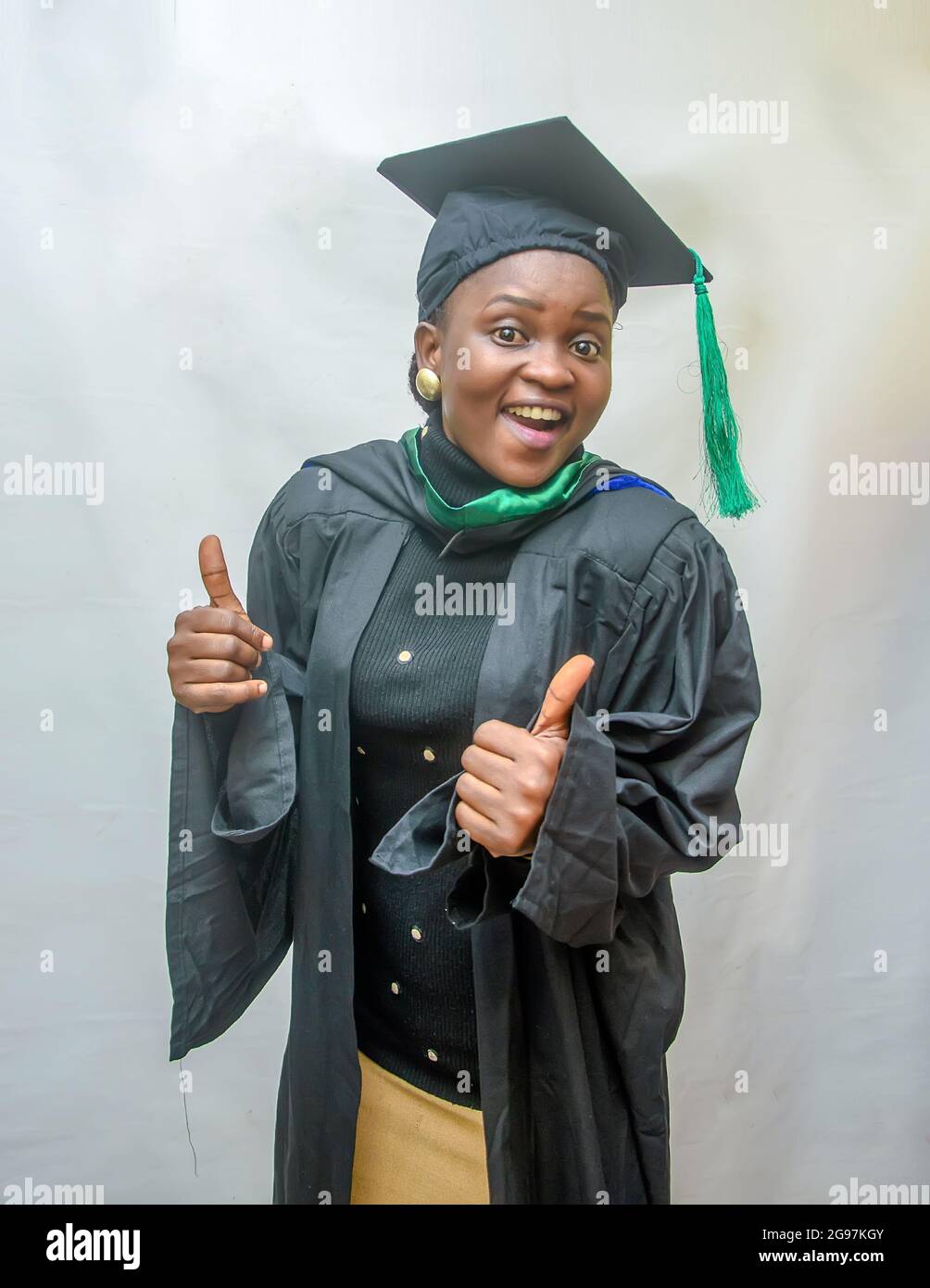Stock photo of an African female graduand or graduating students in her black graduation outfit and joyfully doing thumbs up gesture Stock Photo Alamy