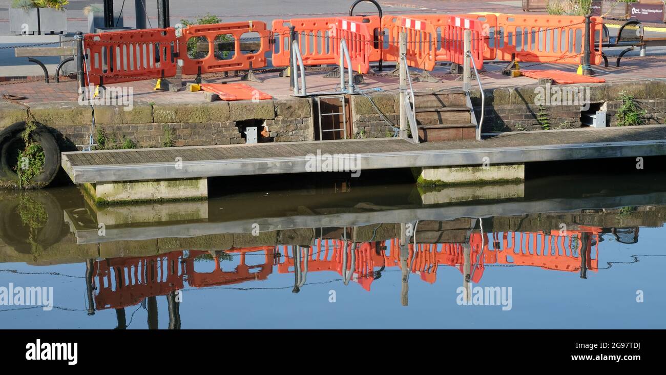 Orange safety barriers reflected in water Stock Photo