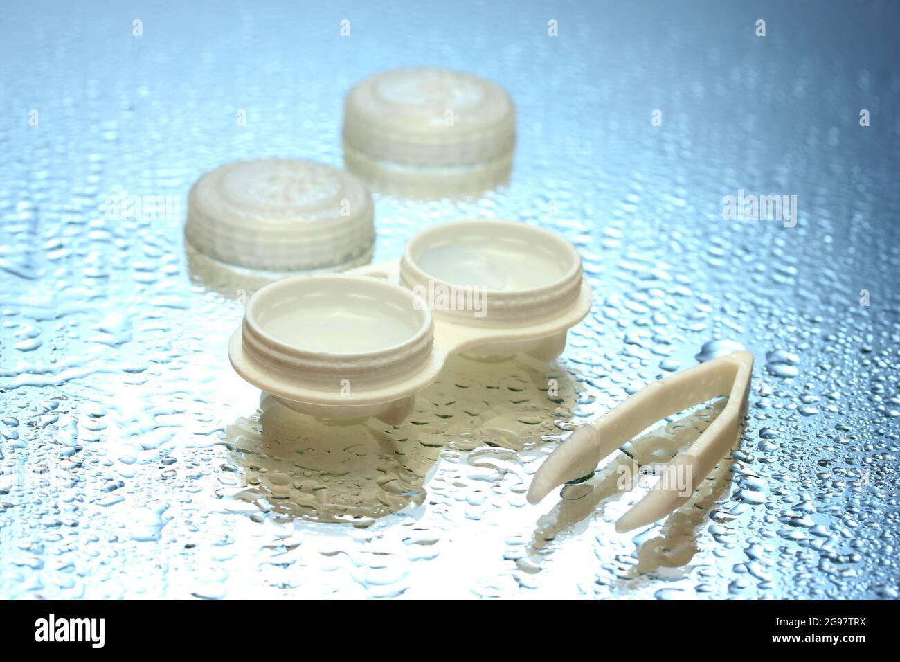 contact lenses in containers and tweezers on blue background Stock