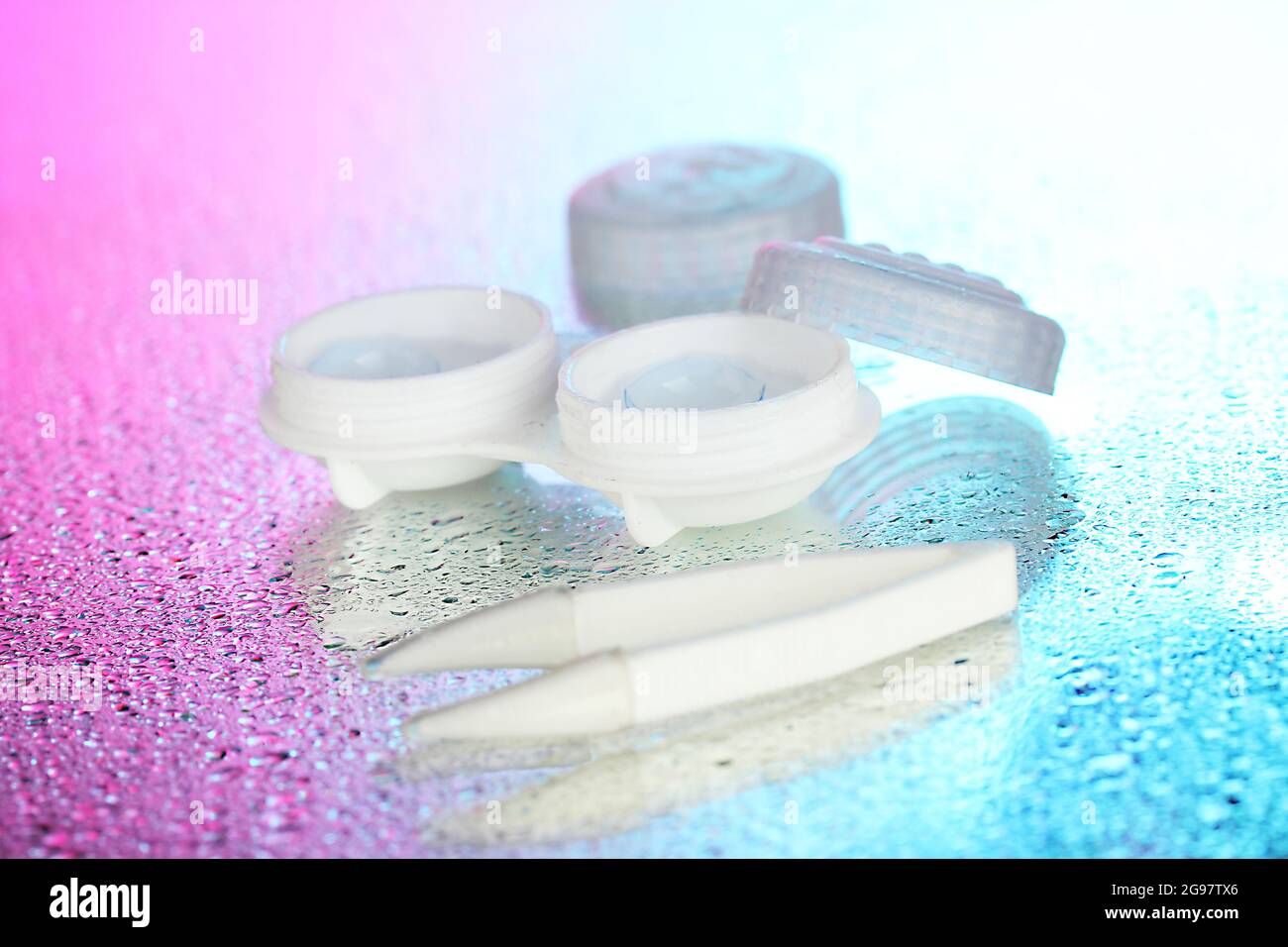 contact lenses in containers and tweezers on bluepink background Stock