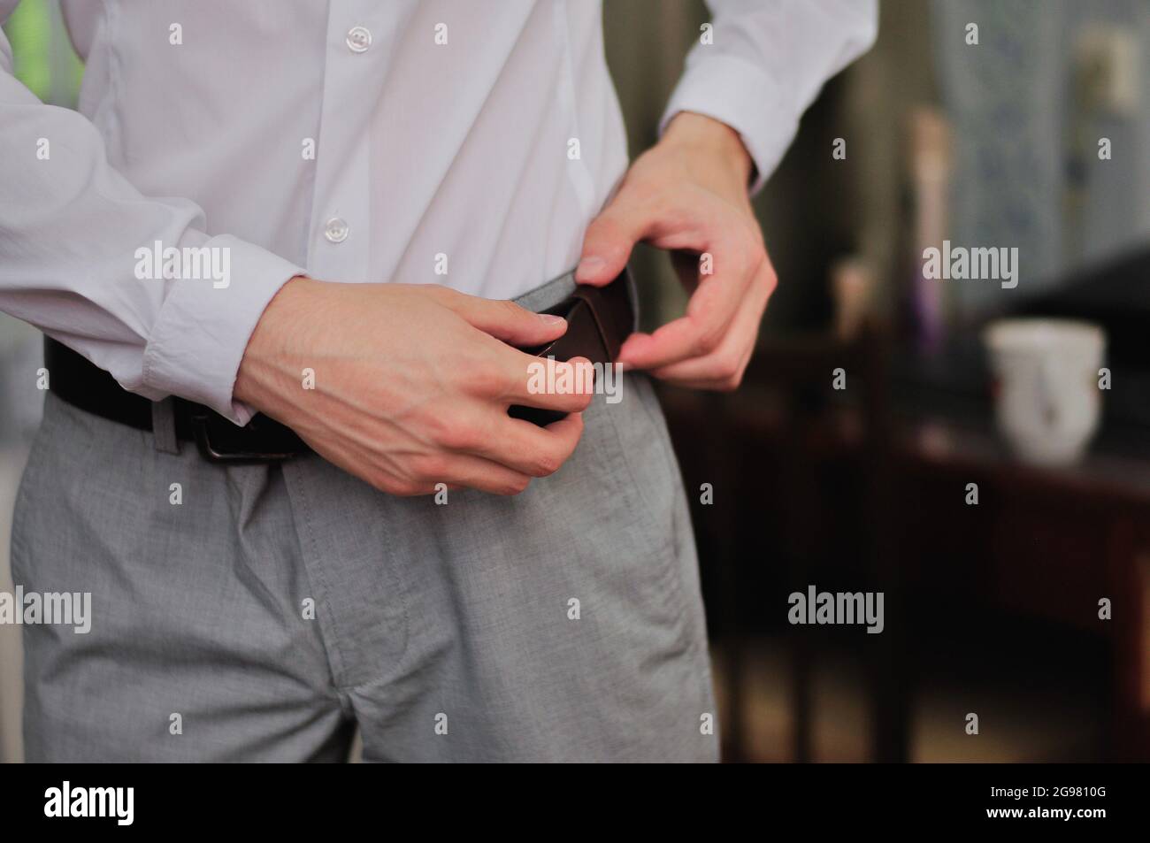 man fastens a belt on his trousers  Stock Photo