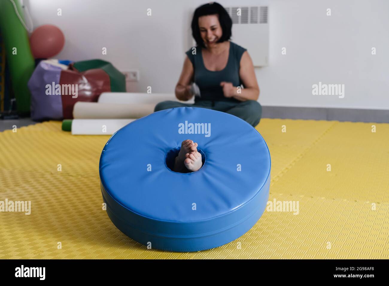 Rehabilitation of children with cerebral palsy. Physical activities for disabled kids in center. Mother, therapist doing exercise with boy on mat Stock Photo