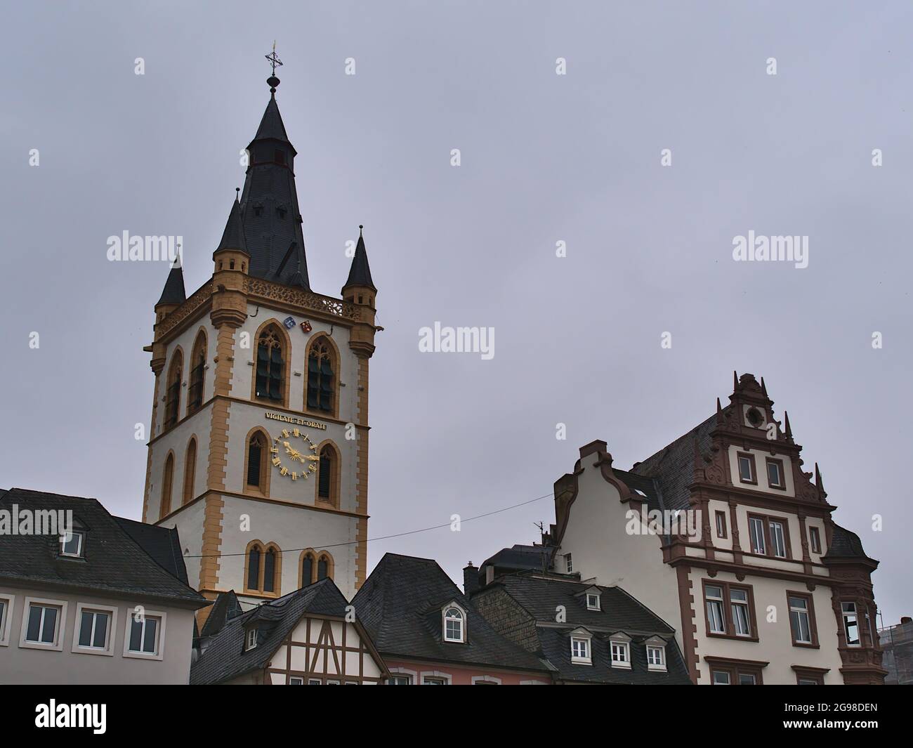Historic old buildings at square Hauptmarkt in city Trier, Rhineland-Palatinate, Germany with steeple of Catholic church St. Gangolf on cloudy day. Stock Photo