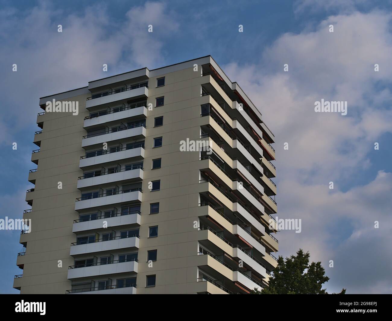 Low angle view of typical residential multi-family high-rise building with apartments and balconies built ca. 1970 on sunny summer day with blue sky. Stock Photo