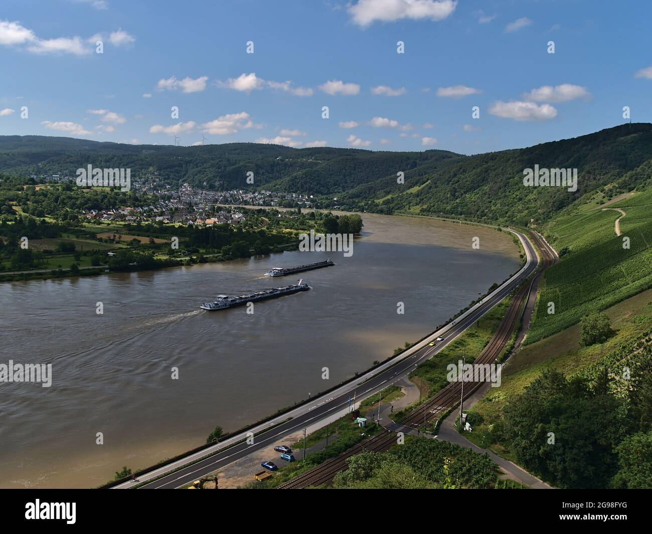 Panoramic view of Rhine valley with two cargo vessels passing by and village Boppard in background in Rhineland-Palatinate, Germany on sunny day. Stock Photo