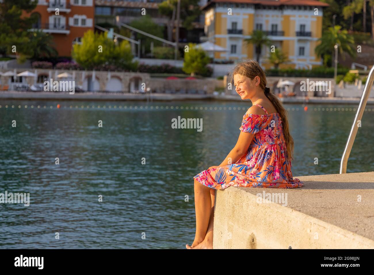 A barefoot female child in a dress on a beach in Mali Losinj, Croatia Stock Photo