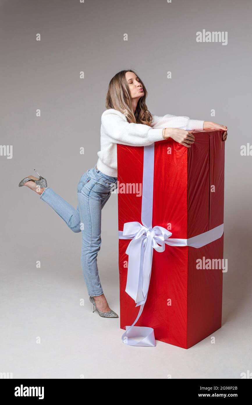 Cheerful girl hugging giant wrapped present Stock Photo - Alamy