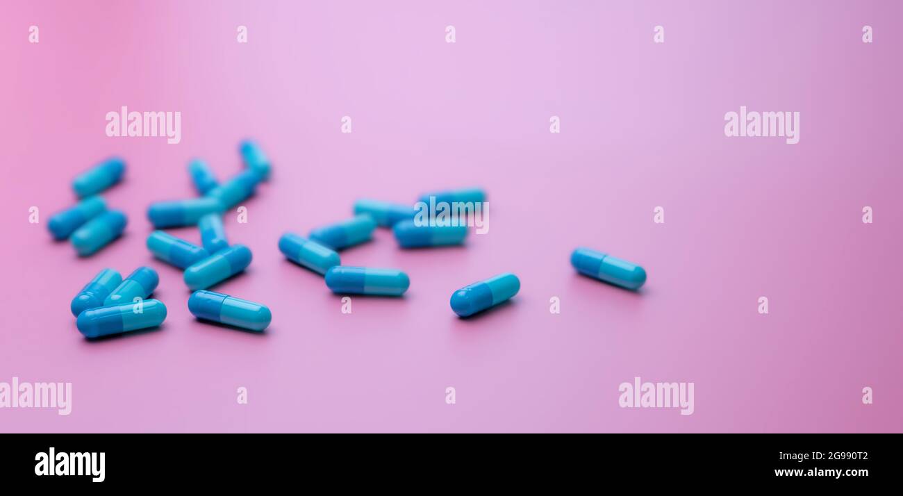 Selective focus on blue capsule pills on pink background. Pharmacy banner. Online pharmacy concept. Pharmacy drugstore product. Pharmaceutical Stock Photo