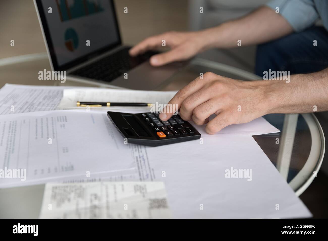 Male works with financial statements using calculator and laptop closeup Stock Photo