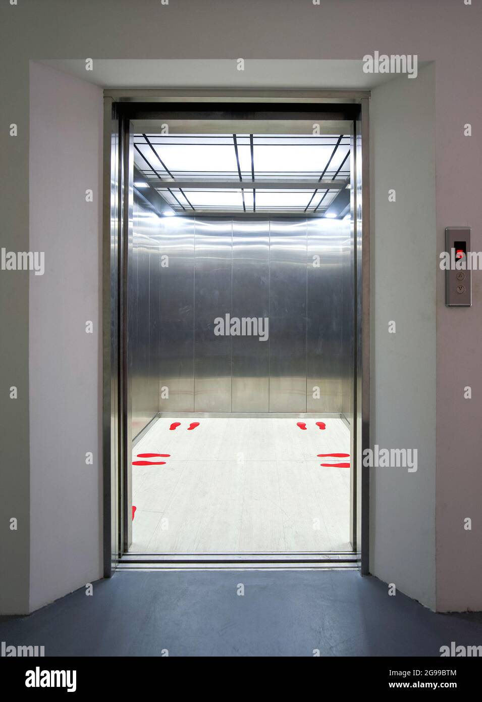 Office building elevator entrance. Red footprint symbol inside the elevator show standing position and distance of each person. Social distancing to r Stock Photo