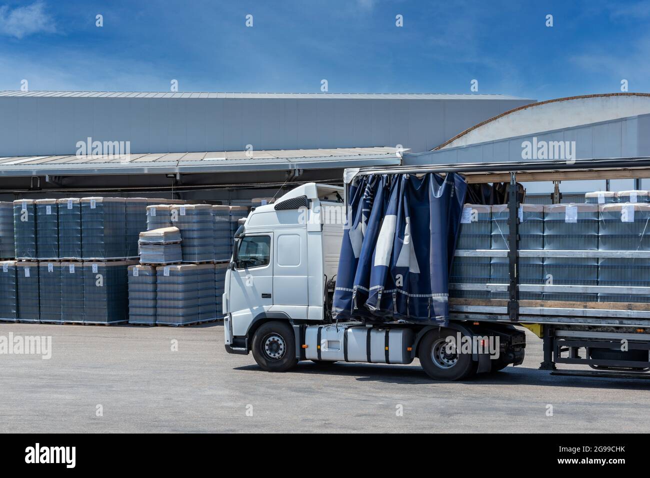Truck with the canvas open loading pallets of empty glass bottles in a factory. Stock Photo