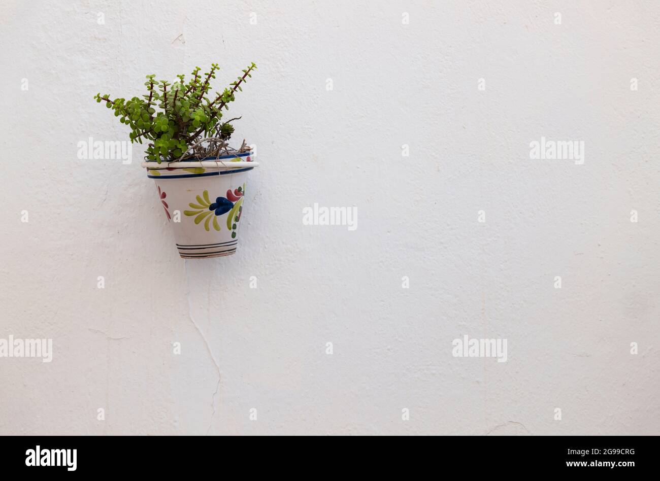 A traditional spanish flowerpot on a white wall Stock Photo - Alamy