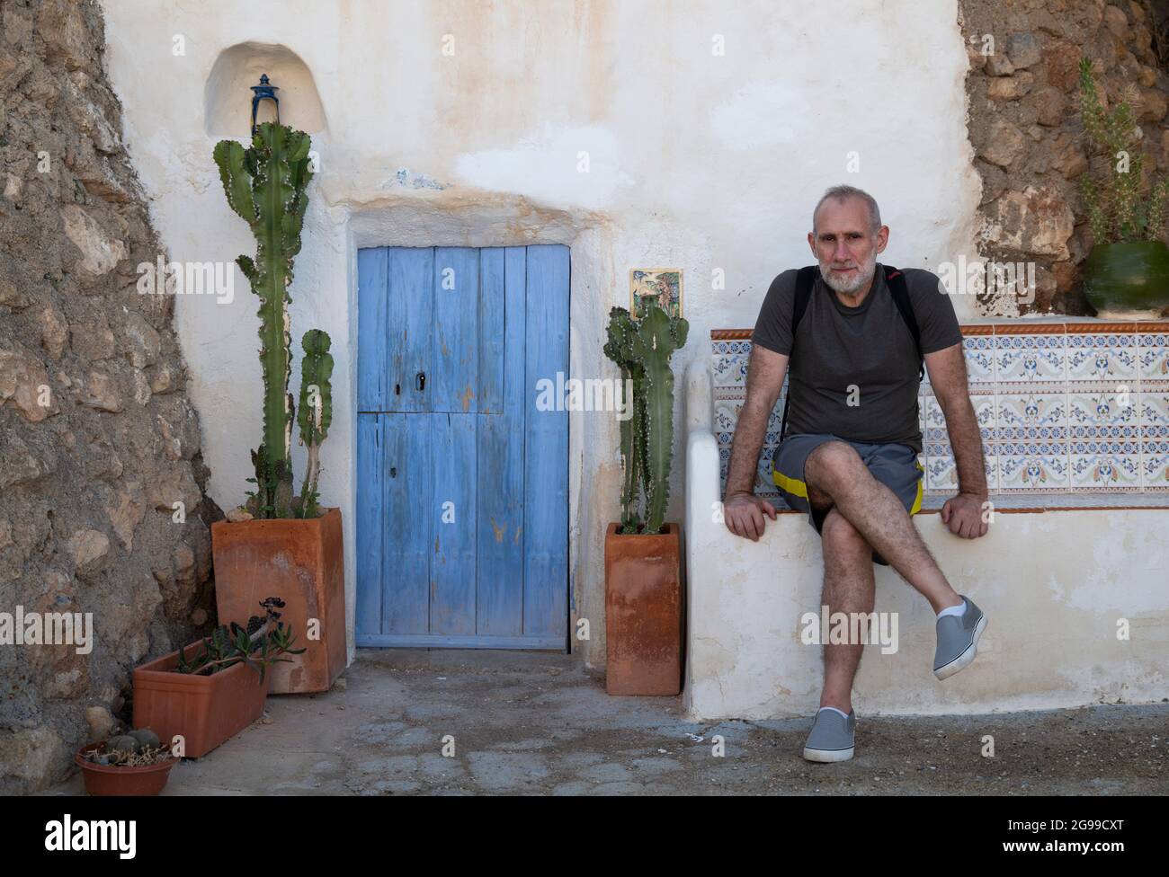 A tourist sitting in front of a cave house in Nijar, a small white village on the south of Spain Stock Photo
