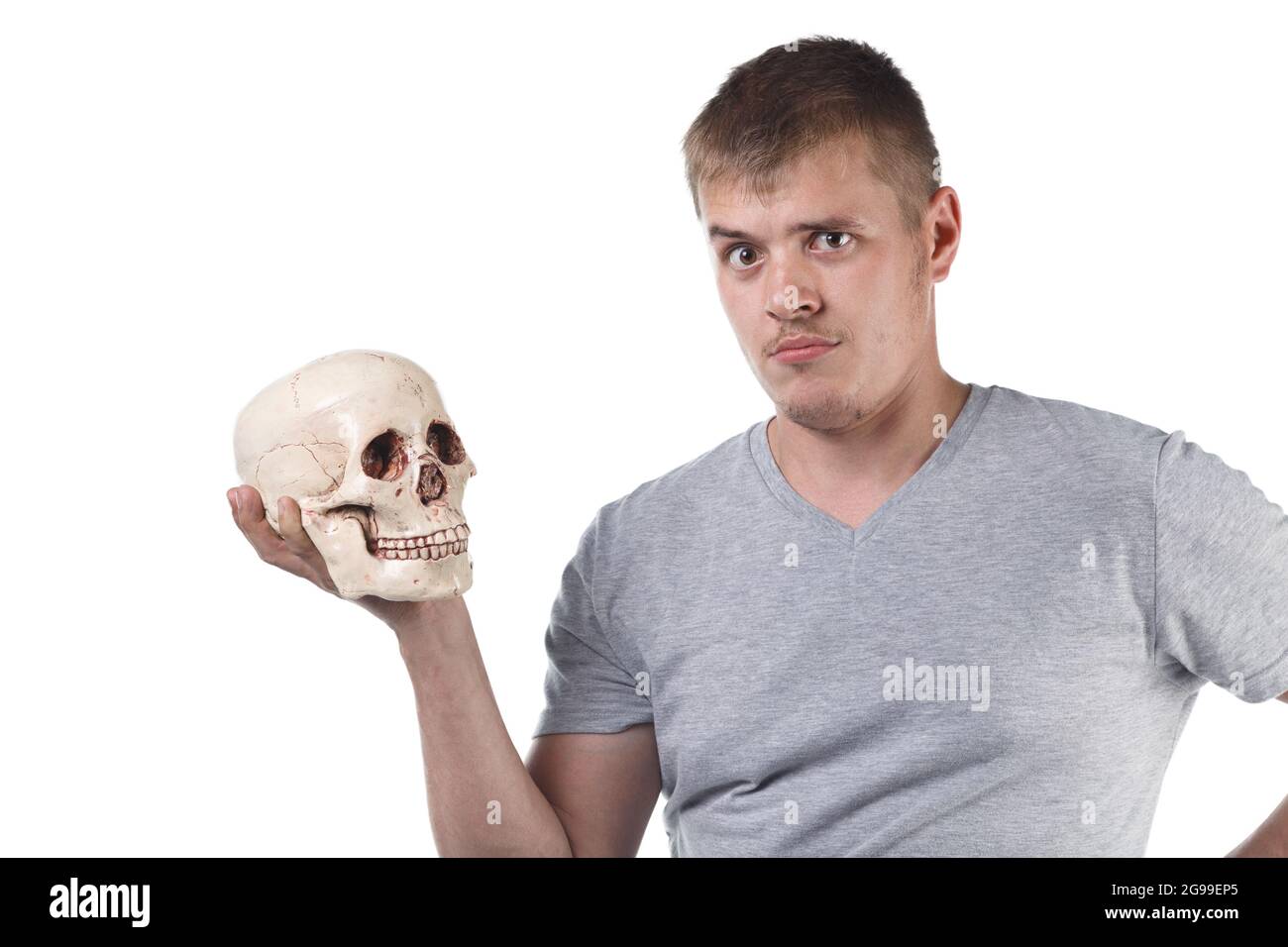 Photo of puzzled man holding human skull Stock Photo