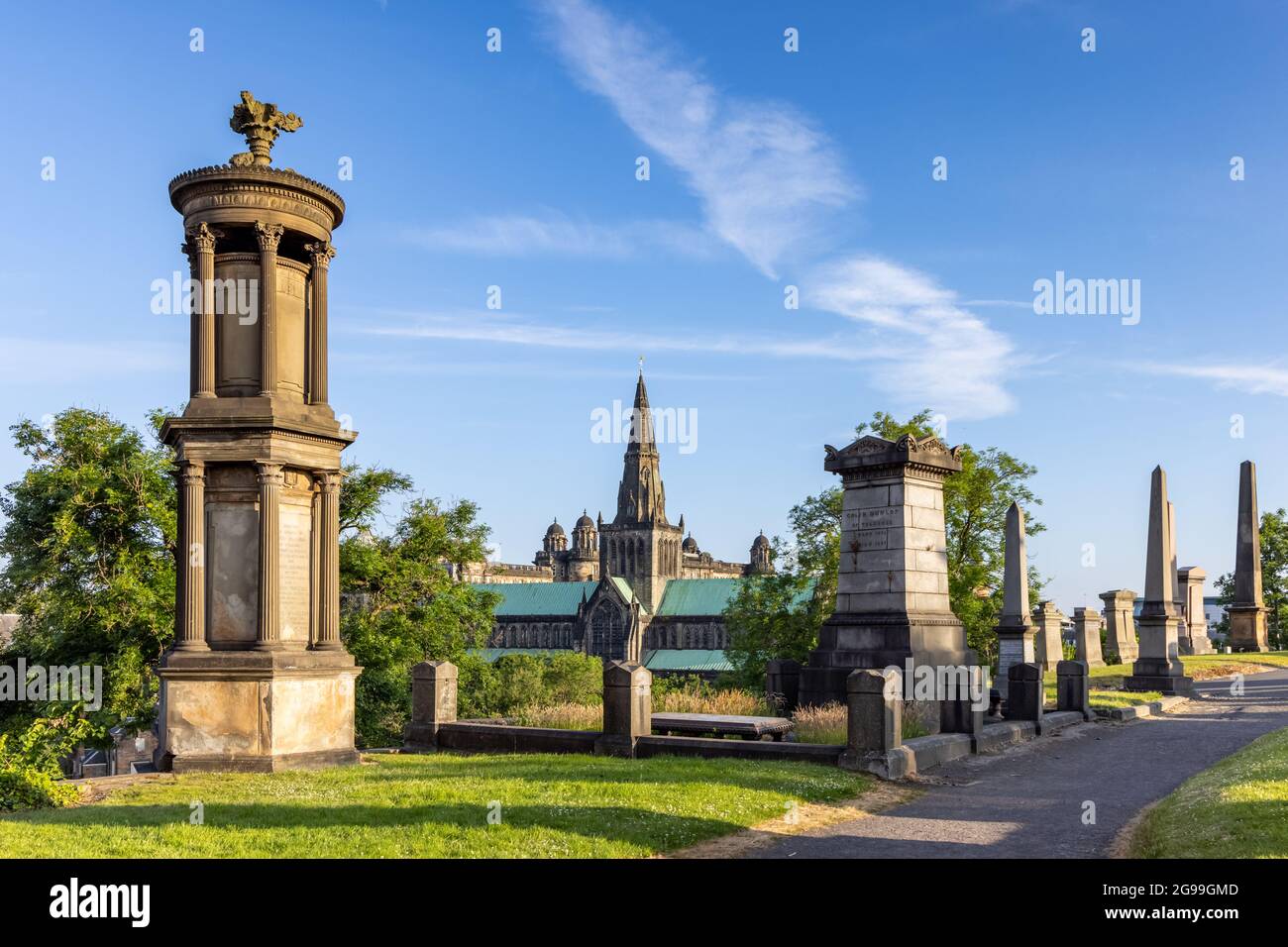 Early morning light casting shadows from the monuments at the Necropolis, a Victorian cemetery in Glasgow, with the Cathedral in the distance. Stock Photo