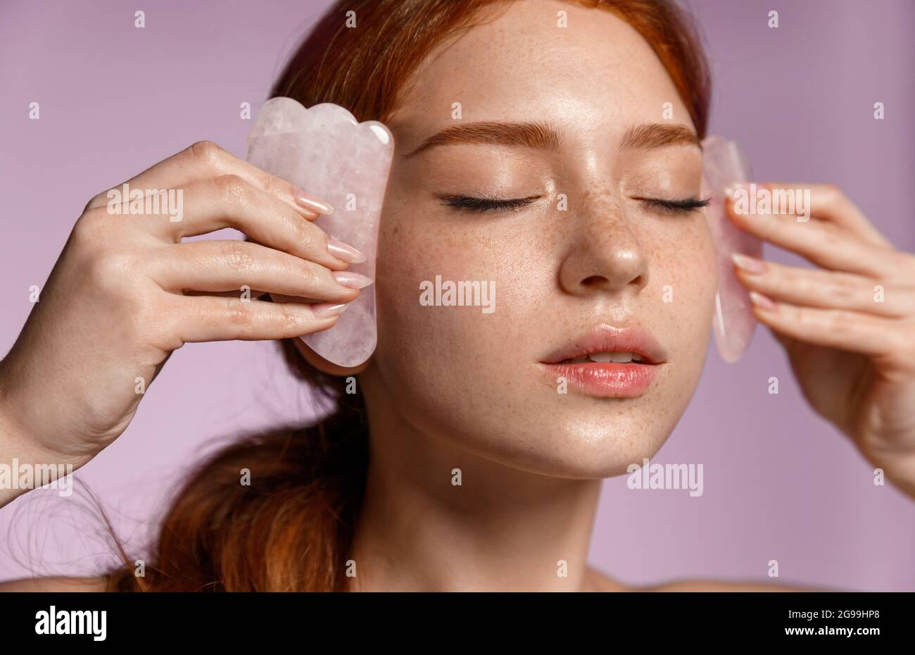 Close up portrait of beautiful redhead girl, ginger female massaging