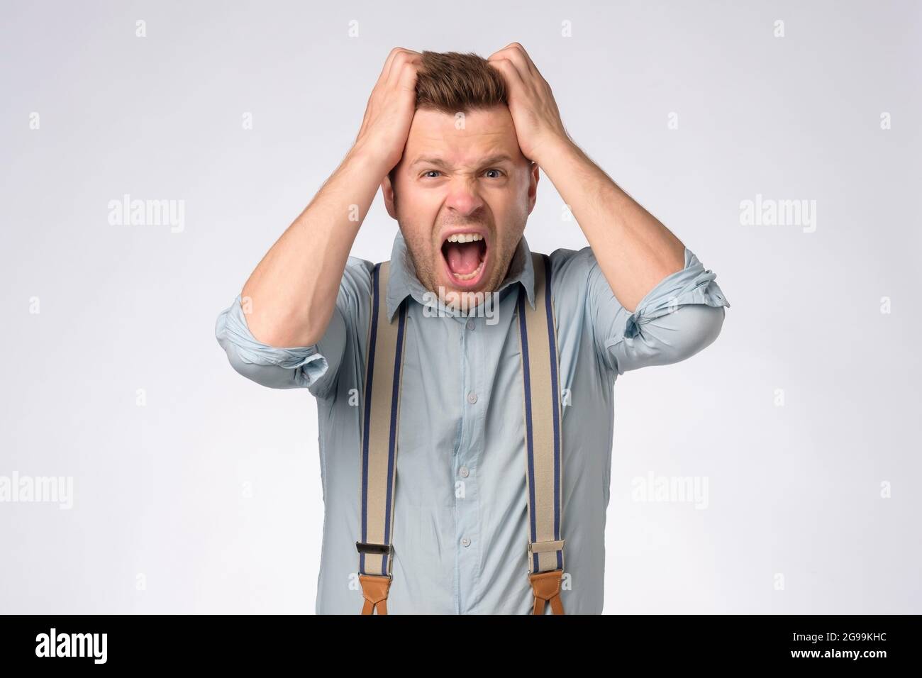 Shocked caucasian man shouting pulling out his hair. Stock Photo