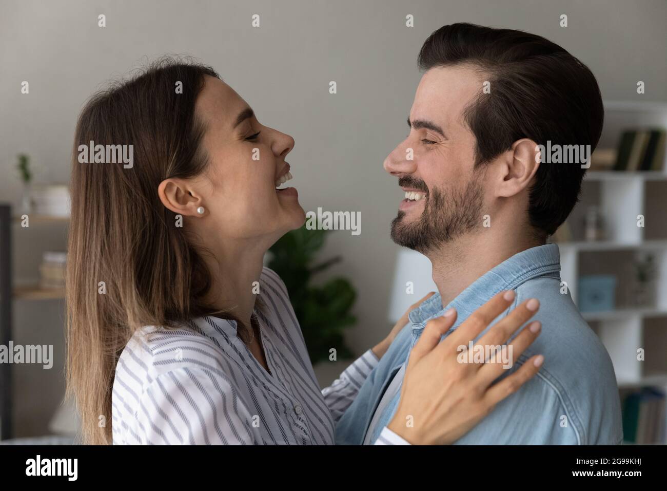 Overjoyed couple looking at each other laughing hugging at home Stock Photo