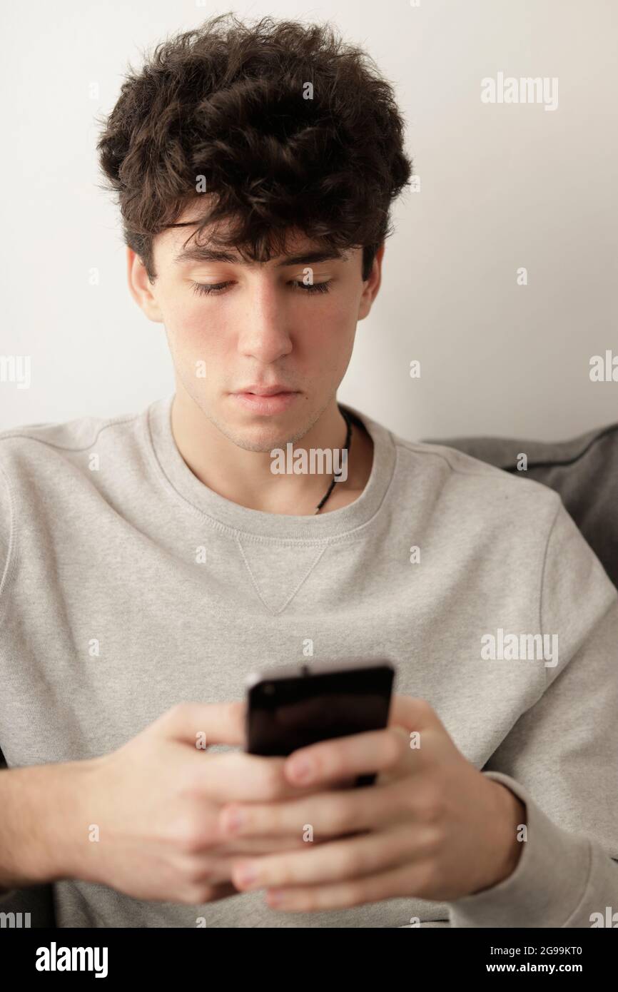 young men writing on his cell phone indoors with neutral color Stock Photo