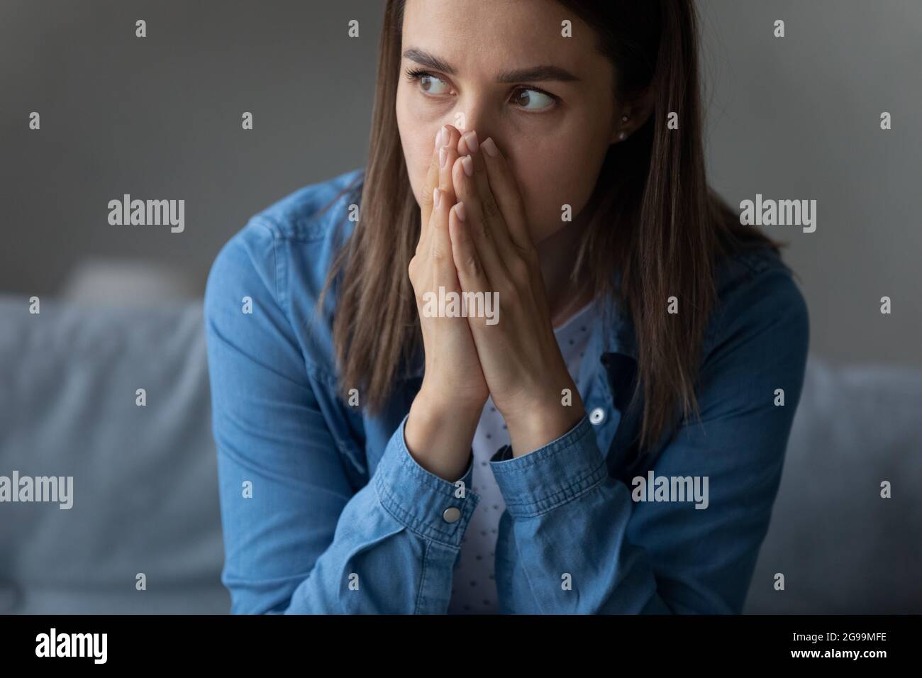 Female sit indoor looks into distance feels horrified by news Stock Photo