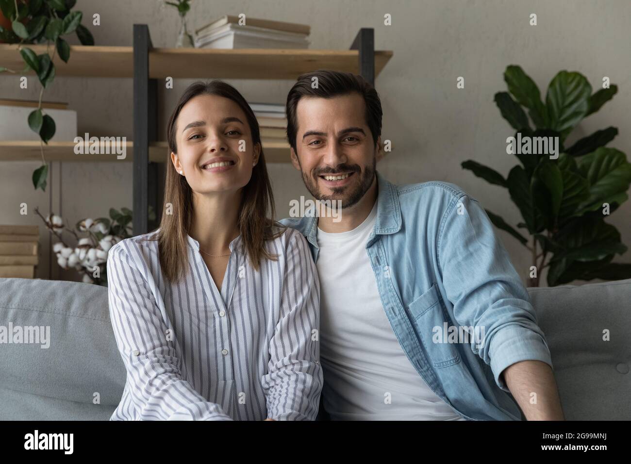 Beautiful married couple sit on sofa smile look at camera Stock Photo