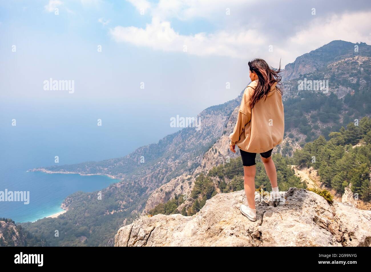 Young girl on top of the mountain looks at the sea view. Stock Photo