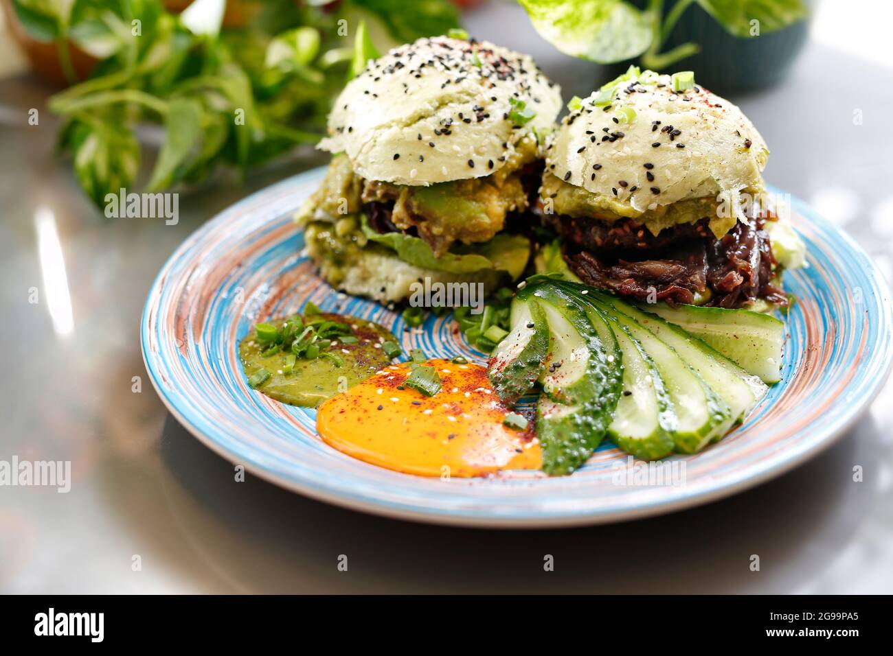Sandwich with vegetables, fried red onion and avocado salad served with fresh cucumber and humus. Dish on a plate, food photography, serving proposal. Stock Photo