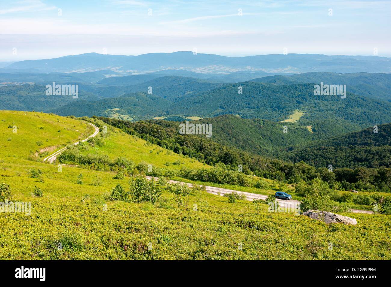 country road through the hill. mountain landscape in morning light. blue sky with clouds on a horizon above the distant ridge. rural valley between th Stock Photo