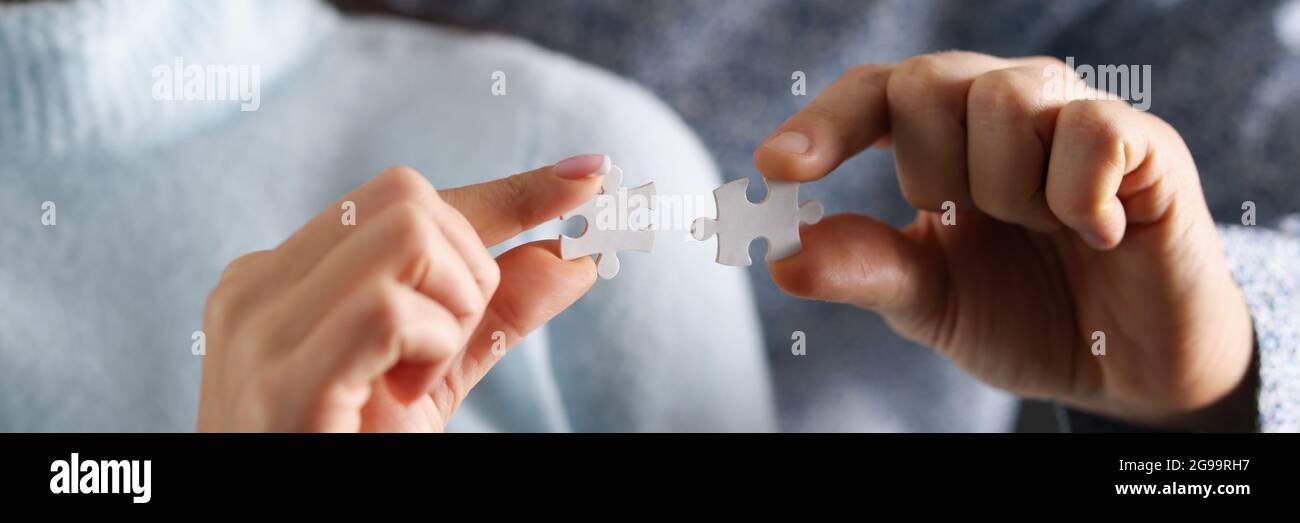 Man and woman are trying to connect white puzzles together Stock Photo