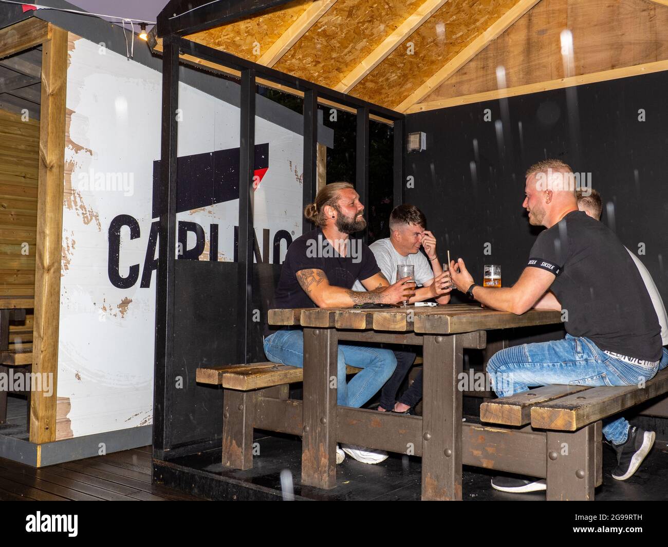 Four male friends drink in an outside booth on a Friday night at Walkabout bar in central Sheffield. Stock Photo