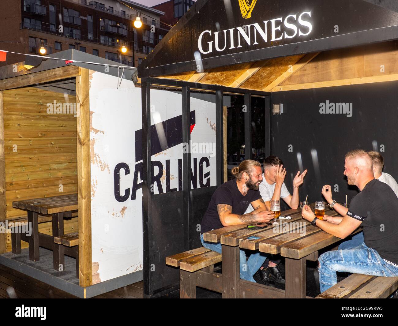 Four male friends drink in an outside booth on a Friday night at Walkabout bar in central Sheffield. Stock Photo