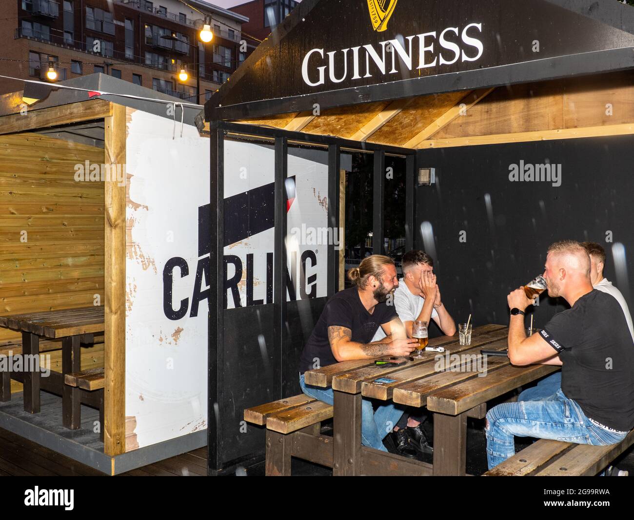 Four male friends drink in an outside booth on a Friday night at Walkabout bar in central Sheffield. Stock Photo