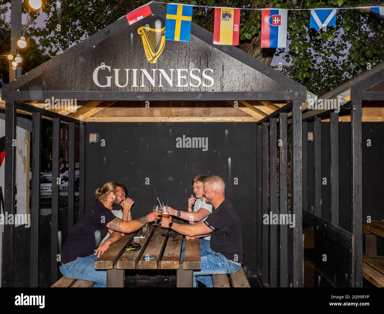 Four male friends drink in an outside booth on a Friday night at Walkabout bar in central Sheffield. Stock Photo