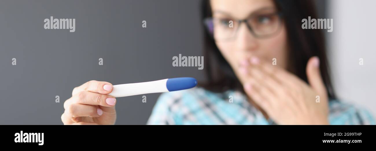Surprised woman holding pregnancy test in her hand Stock Photo