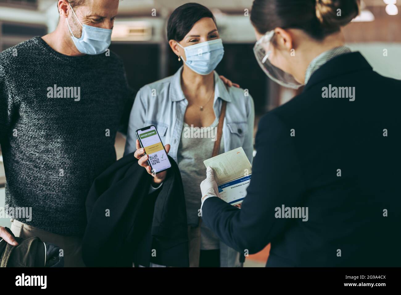 Male and female traveler in face masks at checkin counter displaying