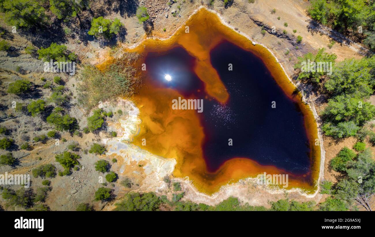 Acidic red lake in place of abandoned open pit copper mine near Kinousa, Cyprus. Aerial view from directly above Stock Photo