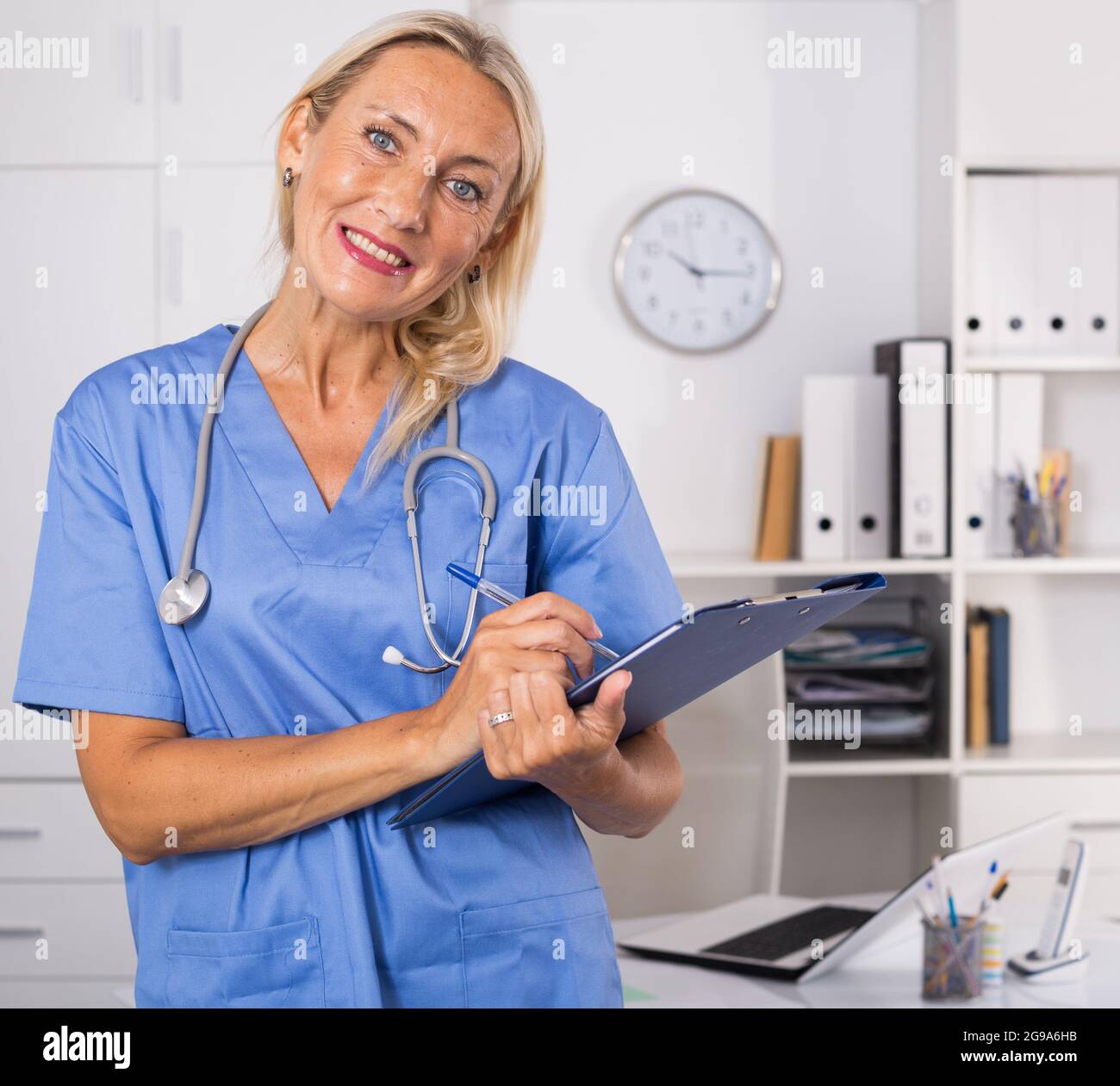Female doctor writing notes on clipboard in clinic Stock Photo - Alamy