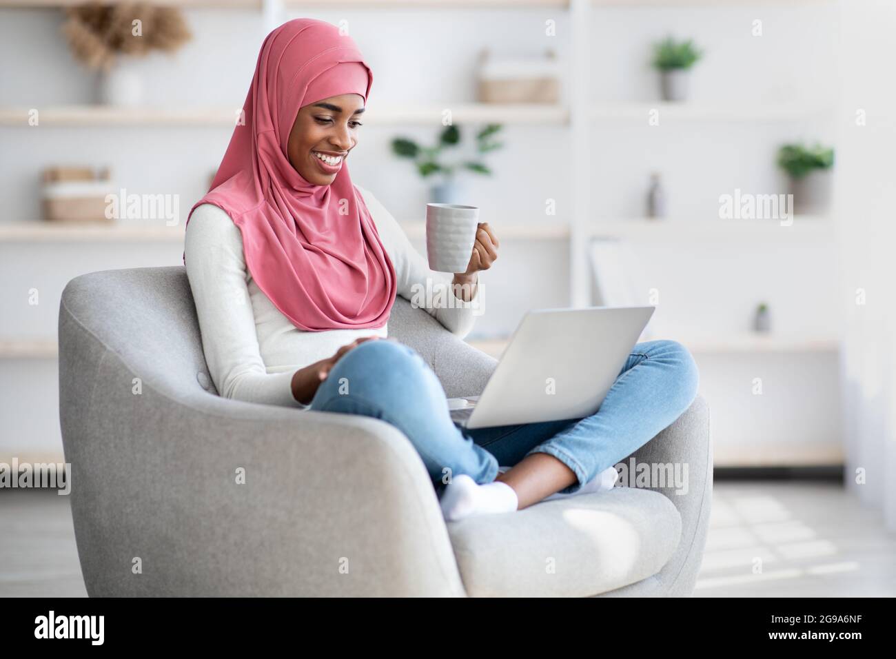Happy Black Muslim Woman Relaxing With Laptop And Drinking Coffee At ...