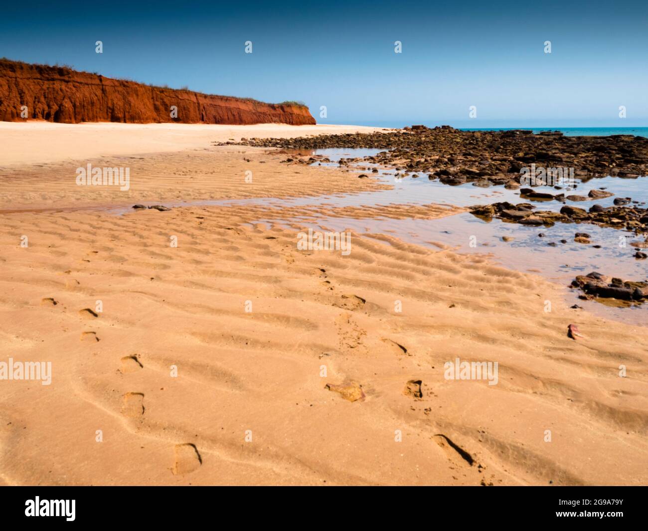 Footprints in the sand and red pindan cliffs at Walmadan (James Price Point), Dampier Peninsula, Kimberley, Western Australia Stock Photo