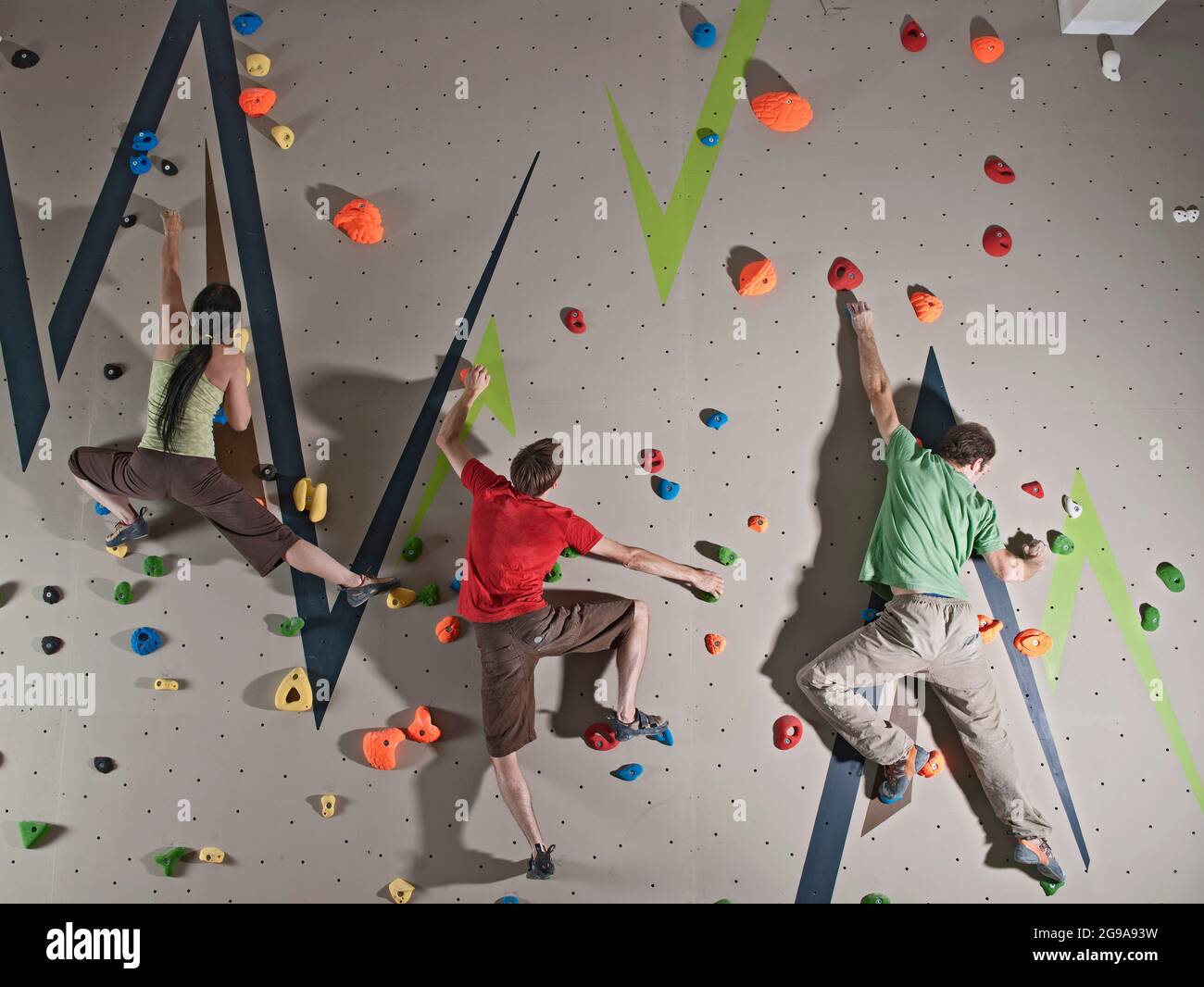 three climbers bouldering at indoor climbing wall in London Stock Photo