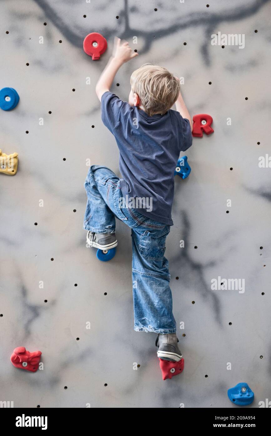 young boy climbing on indoor bouldering wall Stock Photo