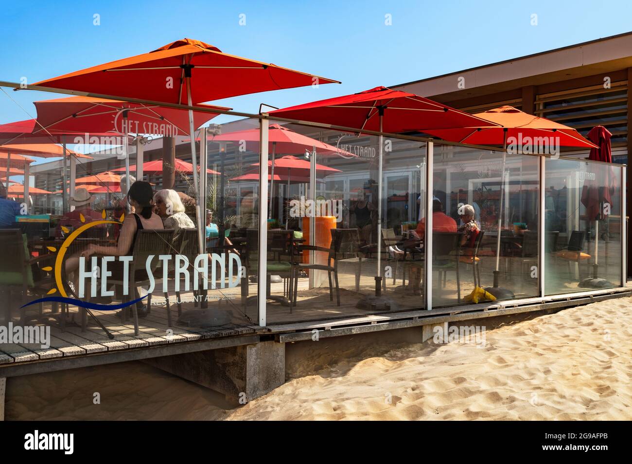 Seaside visitors relaxing at a beach pavilion and enjoying the sunny