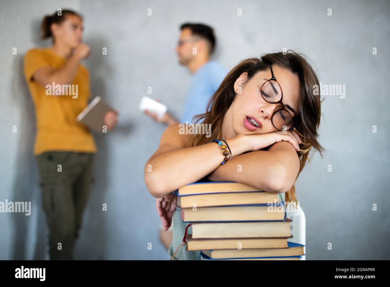 Tired female student sleeping on the books in the library Stock Photo ...