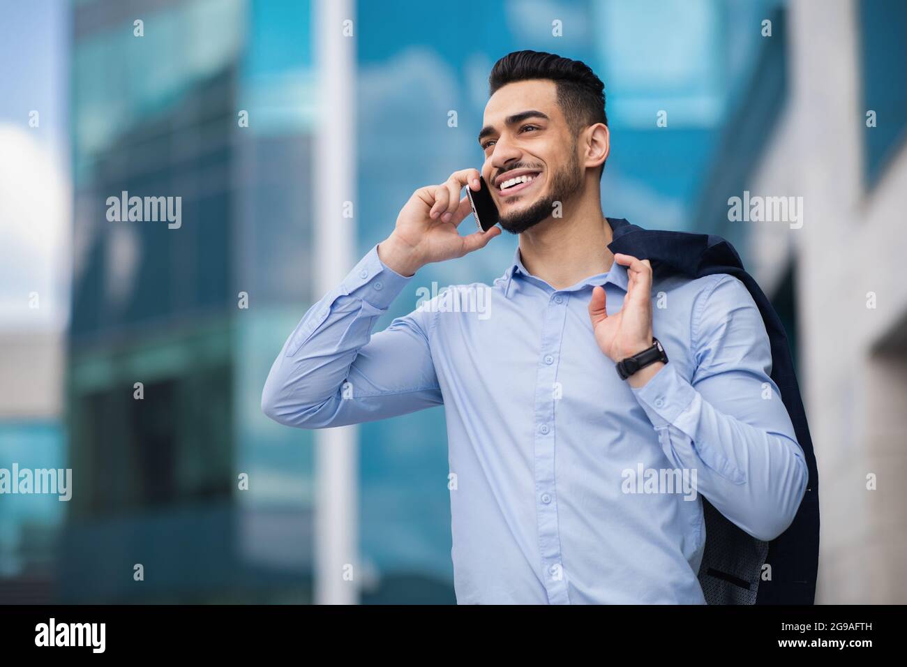 Happy muslim entrepreneur going home from job, talking on cellphone Stock Photo