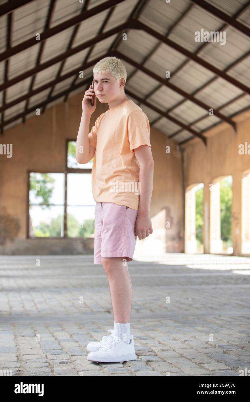 teenager dressed in pastel color talking on cell phone turning to camera Stock Photo